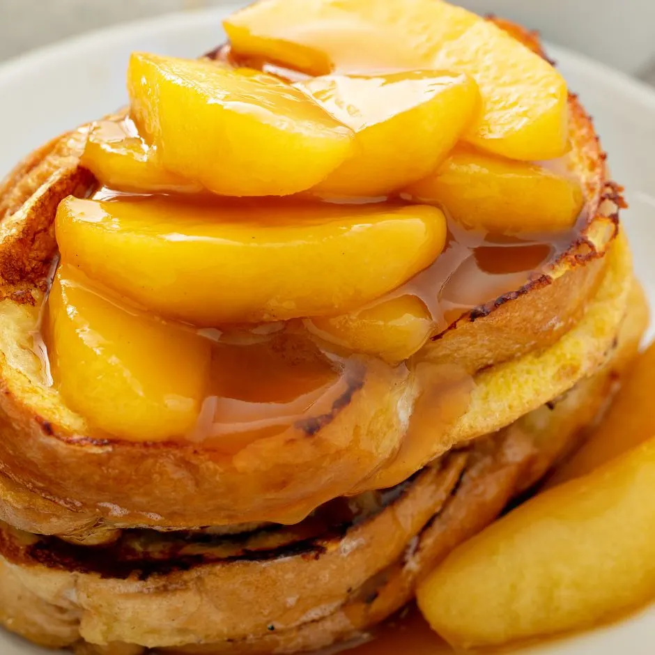 Stack of apple cinnamon French toast drizzled with syrup.
